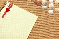 Yellow Checkered Notepad with bookmark in sand. Background with space for text or image
